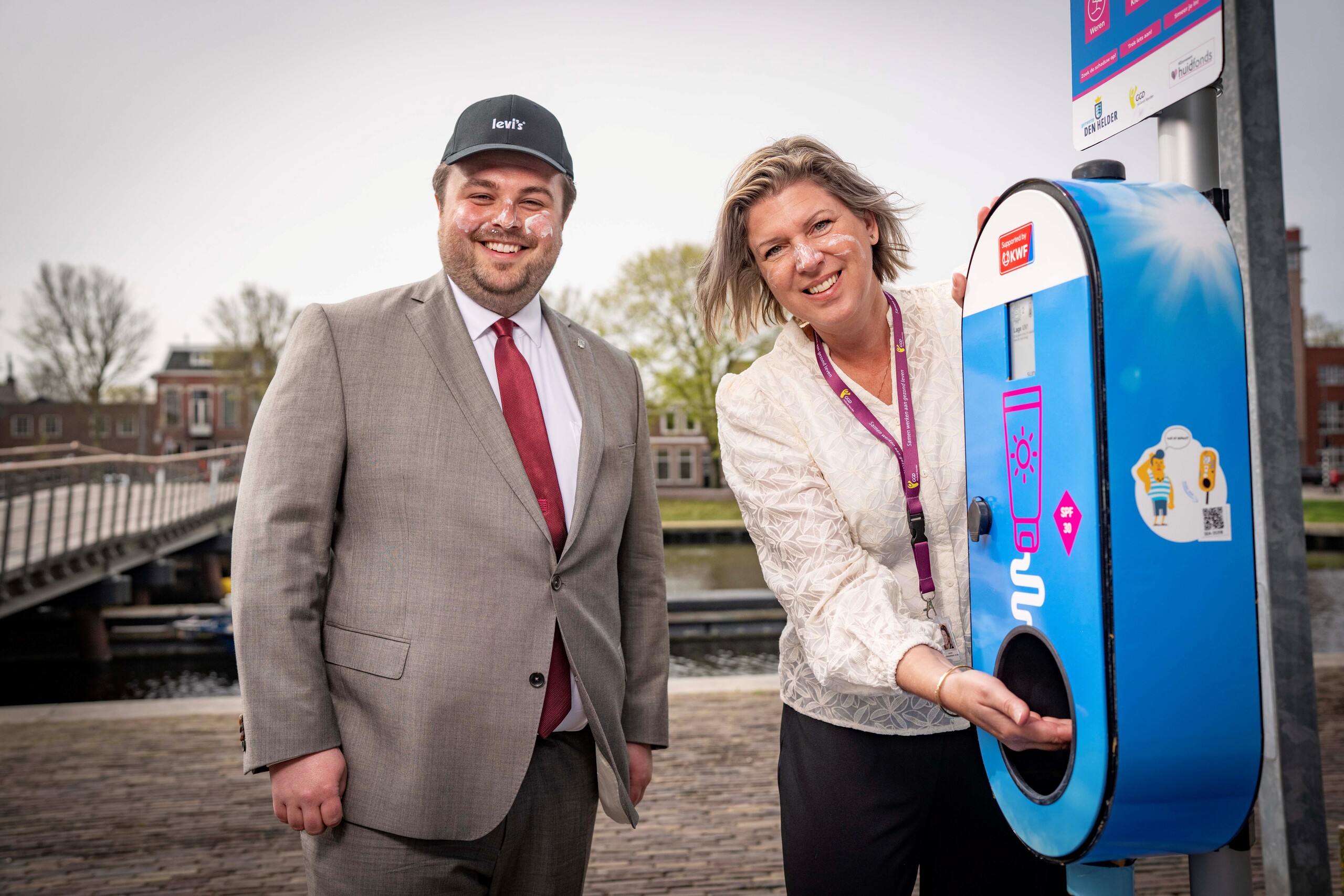 Niels Nanning en Maaike Verharen bij de zonnebrandcrèmepaal op Willemsoord met zonnebrandcrème op hun gezicht