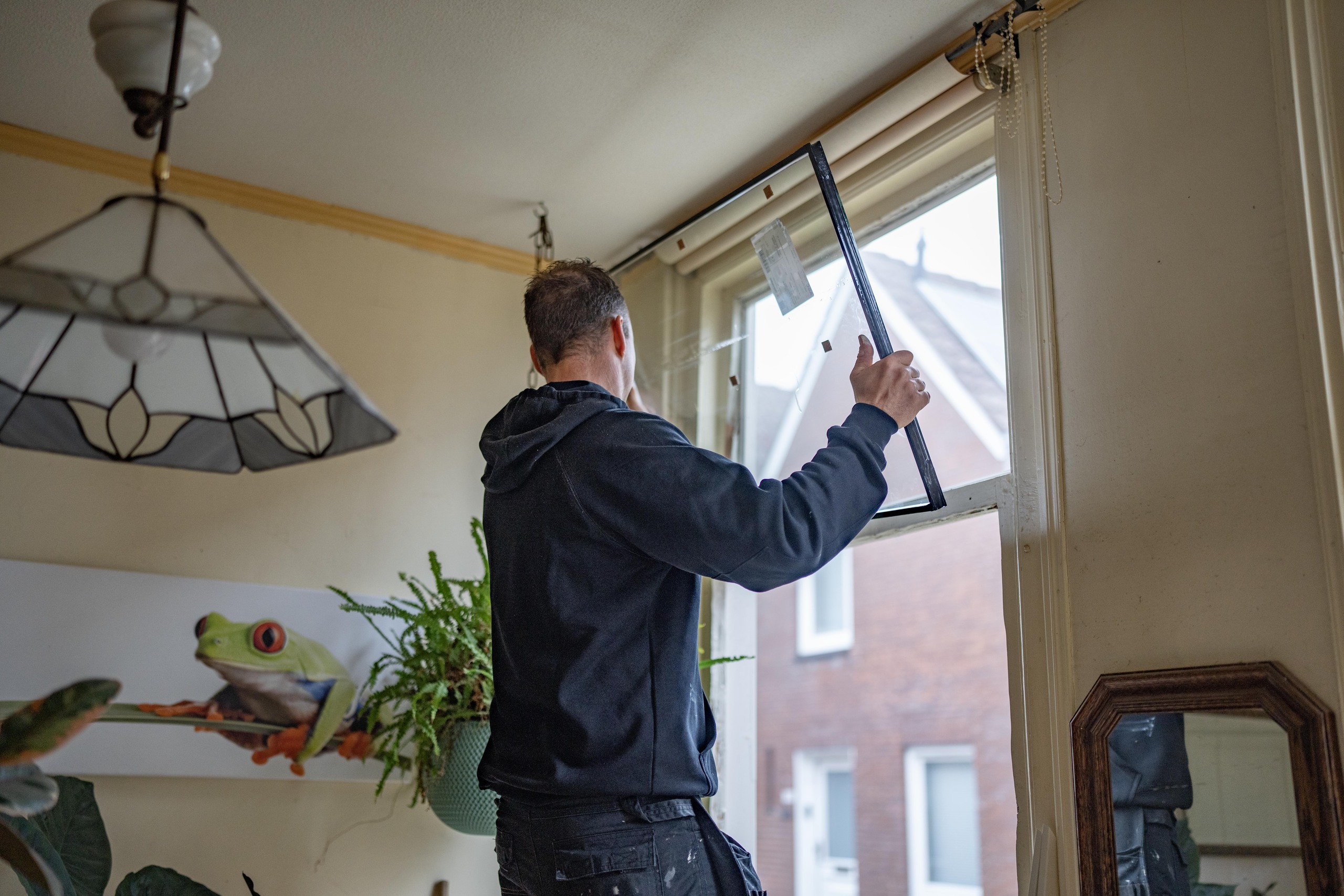 Man plaats nieuw raam in woning