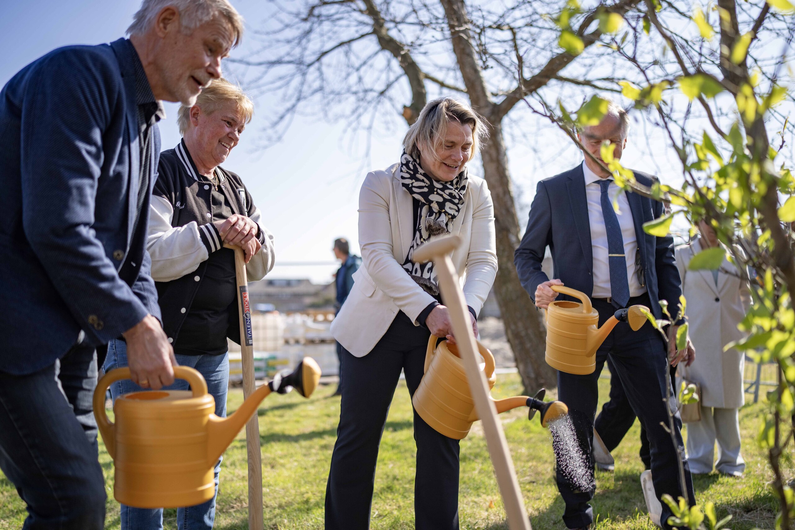 wethouder Petra Bais, Gerrit Seegers van bouwbedrijf Dozy, Ton op ’t Ende van Woningstichting Den Helder en bewoners met gieter